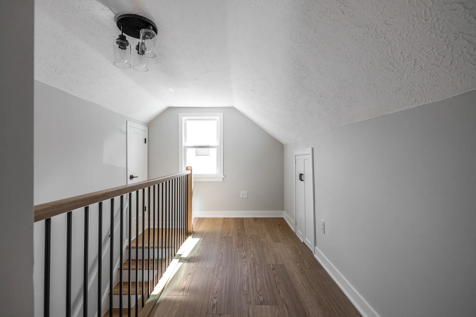 Finished upstairs hallway with iron spindle railing, LVP flooring, and new closet doors